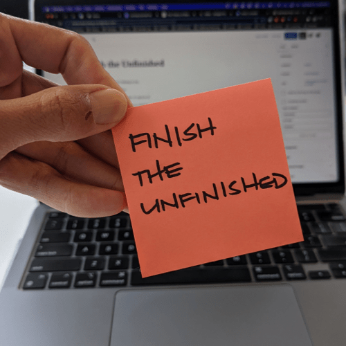 Pink stickie note with the words, "Finish the Unfinished"